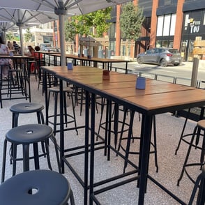 Tables hautes en bois avec structures métalliques noires, mobilier de terrasse sur mesure fabriqué par un métallier ferronnie