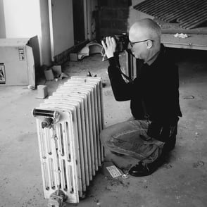 Photographe accroupi près d'un radiateur