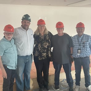 Group photo with five people wearing hard hats at PAH! Apartment construction site