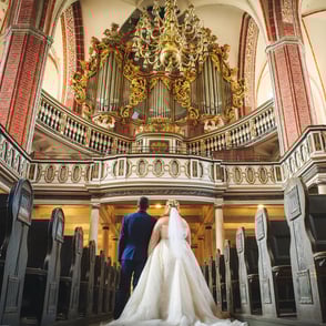 Brautpaar in einer Kirche vor einem kunstvoll geschmückten Altar.