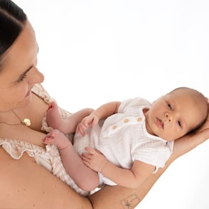 photo de bébé porté dans les mains de sa maman
