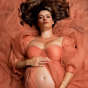 Femme enceinte allongée sur le dos sur une robe de tulle beige pour une photo intemporelle