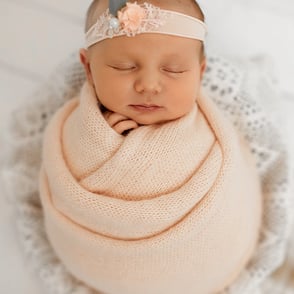bébé dort dans un pot et enrobé d'un wrap de laine pastel