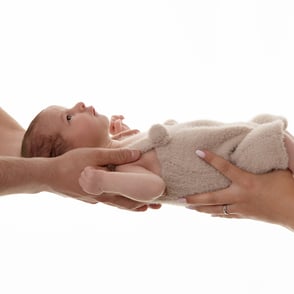 photo de bébé réveillé et porté dans les mains de papa et maman
