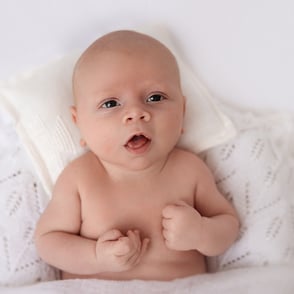photo de bébé qui me regarde couché sur le petit pouf blanc