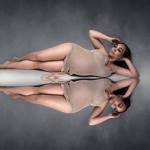 femme enceinte couchée au sol et en miroir dans l'eau