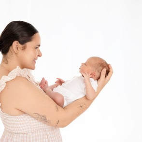 Photographie de nouveau-né dans les bras en face du visage de sa maman pour plein de tendresse entre eux