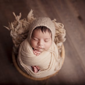 Photo de bébé endormi avec ses petites mains et ses petits pieds dépassant de son wrap et de ses douces couvertures