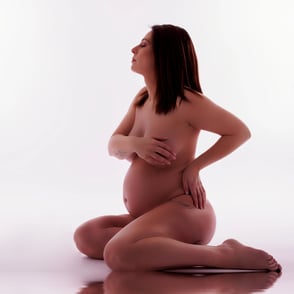 photo de femme enceinte assise au sol nue et en relief dans l'eau