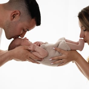 photo de bébé dans les mains de papa et maman avec un bisous sur les pieds
