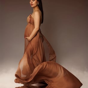 Femme portant des jumeaux avec un voile brun qui vole et un peu de fumée au sol en miroir dans l'eau