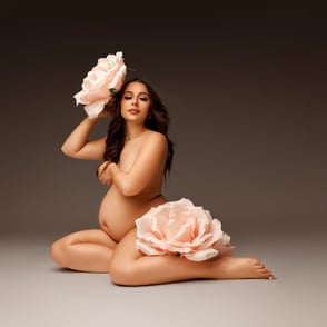 photo de femme enceinte assise et entourée de belles fleurs rose pastel