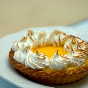 A lemon meringue pie with toasted peaks on a white plate.