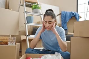 Stressed woman surrounded by moving boxes before a cleanout by West Linn Junk Removal