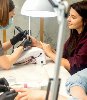 A woman receiving professional nail care from a skilled technician