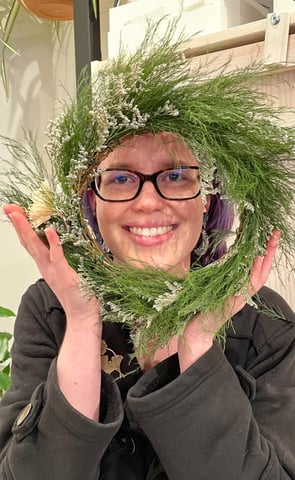 a woman holding a wreath of pine needles