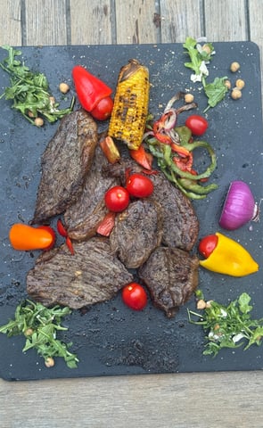 a platter of steaks and grilled veggies