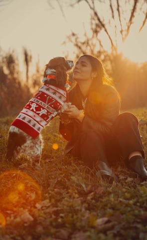 un cane con pettorina natalizia di lana su due zampe si avvicina alla padrona