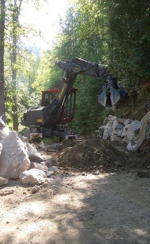 spider hoe being used for building a rock retaining wall