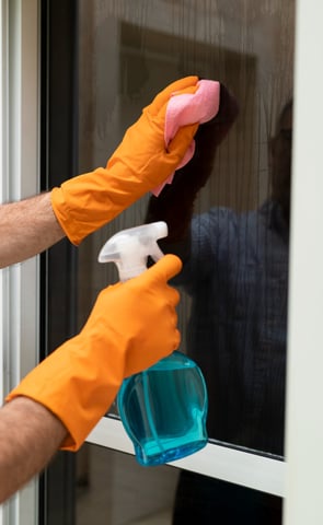 a man cleaning a window with a spray bottle
