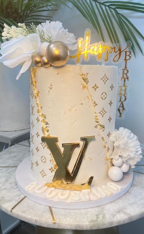 a cake with a gold foil lettered on top of a table