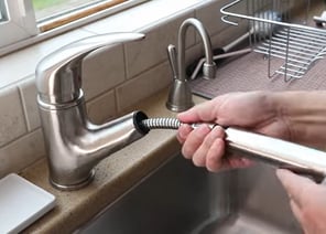 unscrewing the nut from the faucet for the replacement