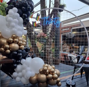 30th birthday party setup at the Brunswick Hotel with a white circle backdrop Thirty neon sign and balloon garland