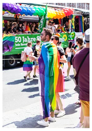 Ein Mann trägt eine Regenbogenflagge bei der Christopher Street Day Parade in Berlin.