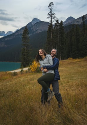 a man and woman laughing during their photoshoot at Lake Louise 