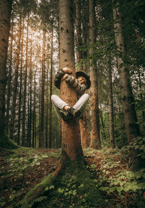 a girl hugging a tree trunk in a forest 