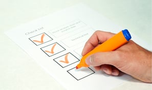 a person holding a pen and writing on a piece of paper