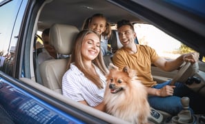 Família feliz com seu cachorro dentro carro com a janela aberta