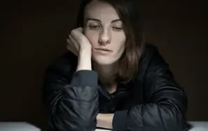 Mulher apoia na mesa com expressão triste