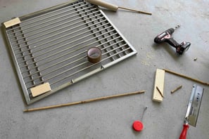 image showing cage door frame with cardboard paper and power drill tool and wood in development