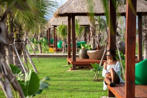 a woman sitting on a bench in a tropical setting