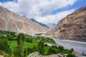 a valley with a river and mountains in the background