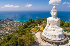 a large white buddha statue sitting on top of a hill