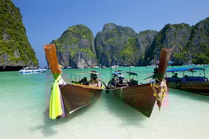 boats in the water with people on the beach