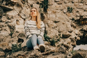 a woman sitting on a rock wall