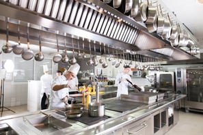 a group of chefs in a kitchen with pots and pans