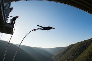 um homem está pulando de uma ponte sobre um rio
