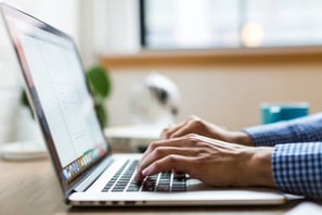 Hands typing a report on a laptop