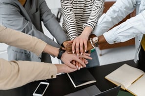 A team celebrating success by putting their hands together