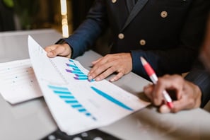 Two members of a team analysing a spreadsheet containing business data and statistics