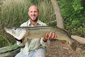 a man holding a fish in a canoe