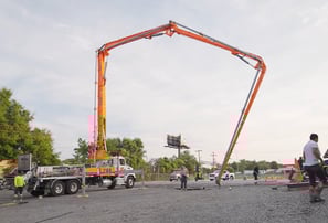Long arm pouring concrete to finish the flat work