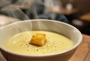 a bowl of soup with a piece of breaded bread