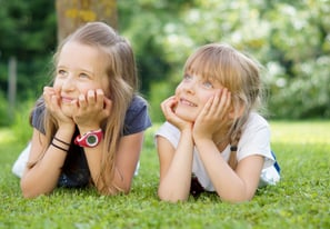 portait d'enfants souriants allongés dans l'herbe