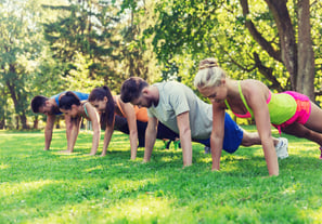 a group of people doing push ups in a park