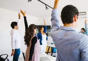 a group of people standing in a room with their hands up